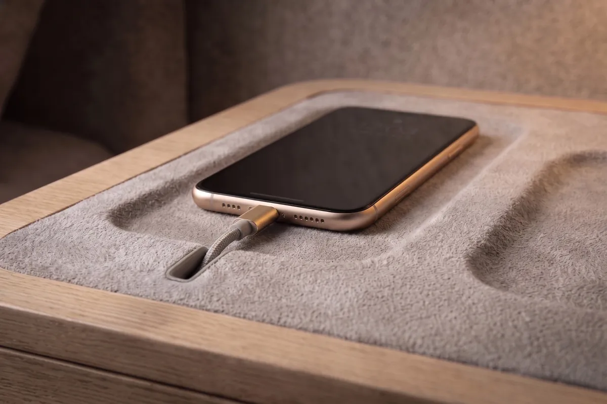 A phone resting in a felt-lined charging tray with a hidden cable channel